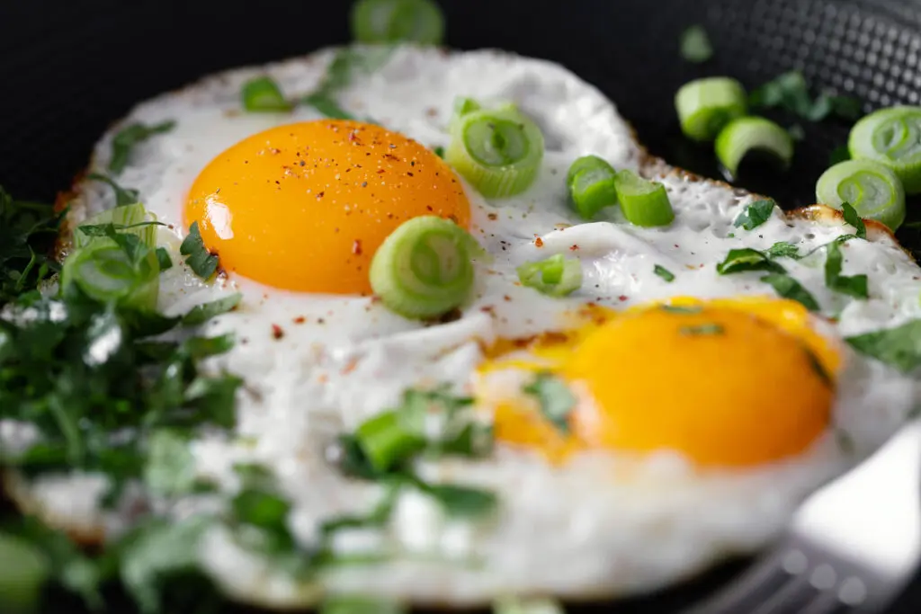 fried eggs with vegetables on pan