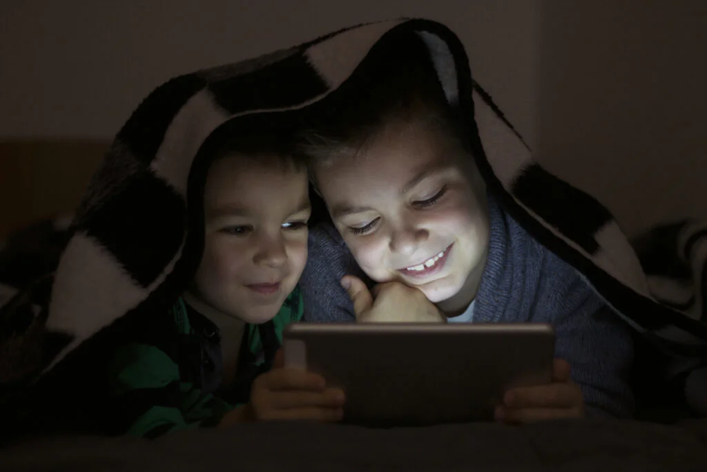 two kids using tablet pc blanket night cute brothers with tablet computer dark room smiling