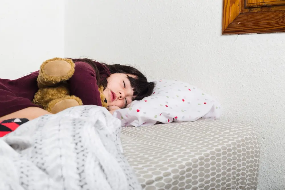 a toddler baby girl sleeping on her bed