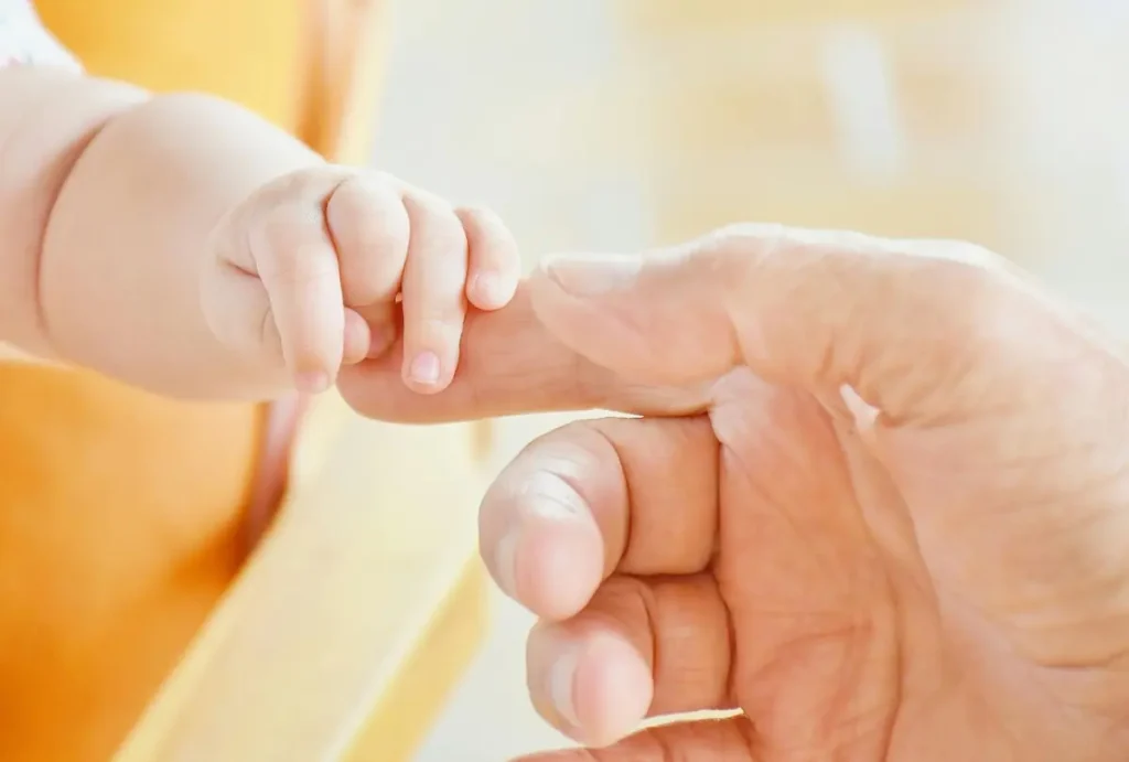 Baby hand grasping adult finger