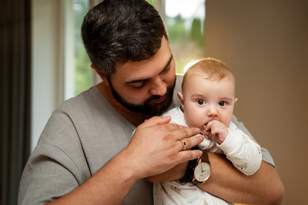 father holding a baby indoors.
