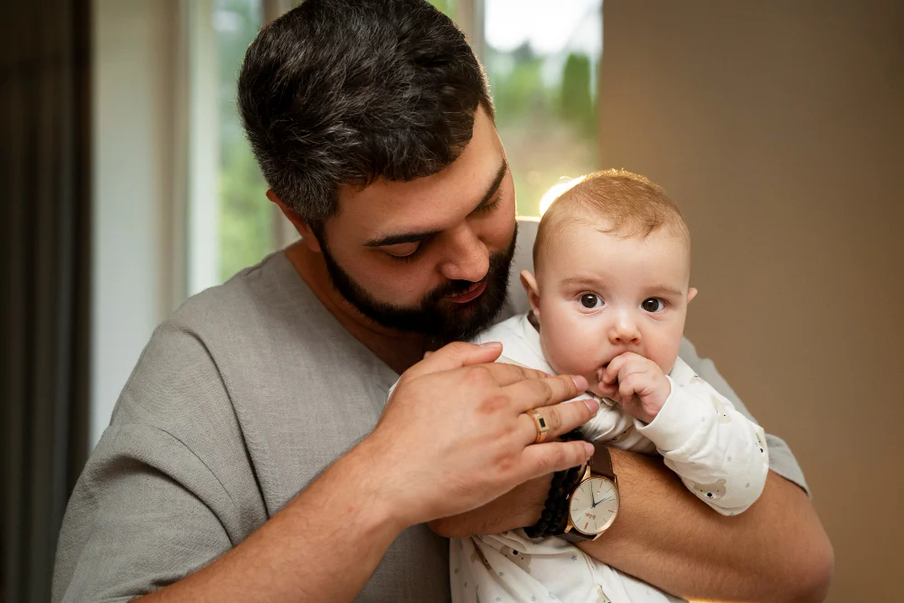 father holding a baby indoors.