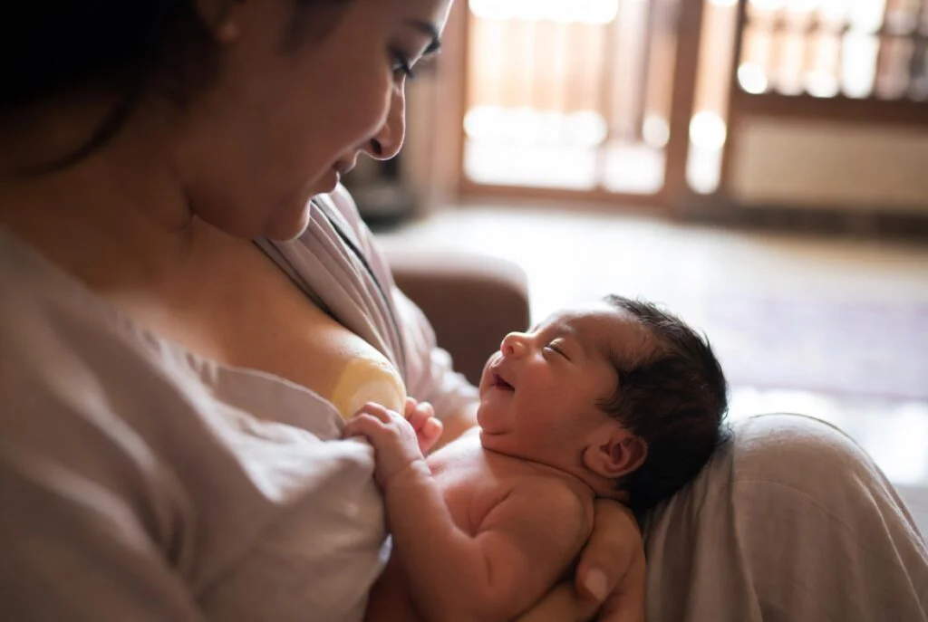 Mother feeding smiling newborn baby.