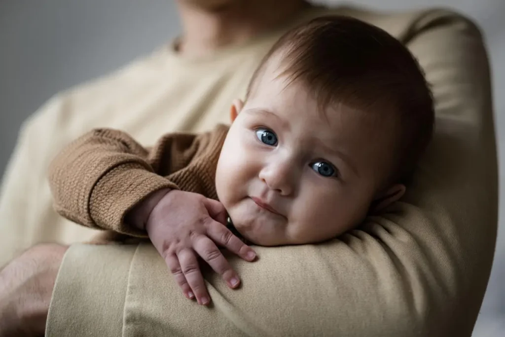4-month-old baby resting calmly on parent’s shoulder