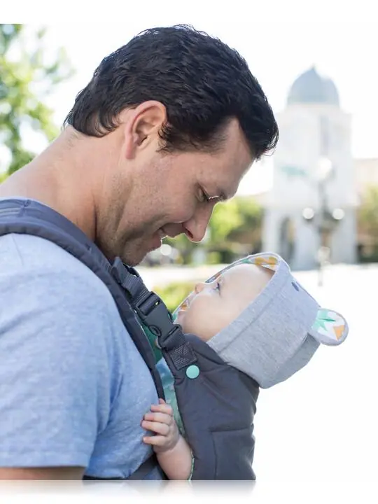 Father bonding with baby in a front carrier outdoors
