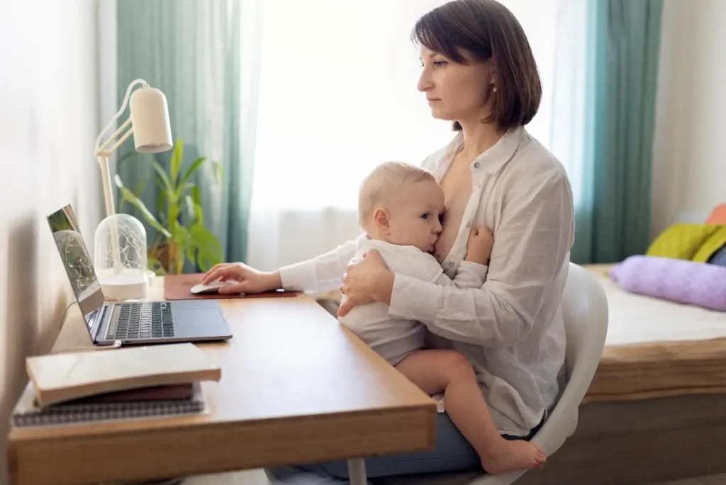 Working women feeding her toddler while doing her work on laptop